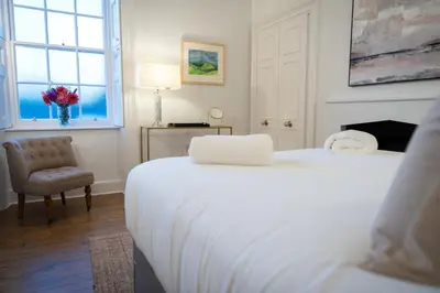 a bedroom with two beds and a chair and a window at Bridge View in Annan
