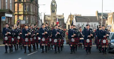 a group of men in kilts marching down a street at Bridge View in Annan