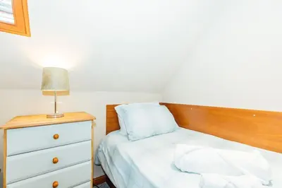 a bedroom with a bed and a dresser with a lamp at Valley View at Clauchan Holiday Cottages in Gatehouse of Fleet