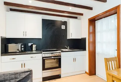 a kitchen with white cabinets and a stove top oven at The Dairy Bothy at Clauchan Holiday Cottages in Gatehouse of Fleet