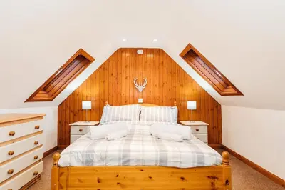 a bedroom with a large bed with wooden walls at The Dairy Bothy at Clauchan Holiday Cottages in Gatehouse of Fleet