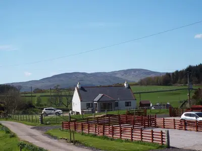 a farm with a fence and a house and cars at The Dairy Bothy at Clauchan Holiday Cottages in Gatehouse of Fleet