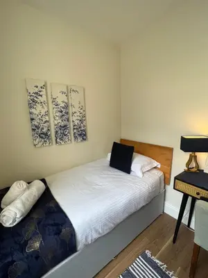 a bedroom with a bed and three paintings on the wall at Elizabeth Grace House in Douglas