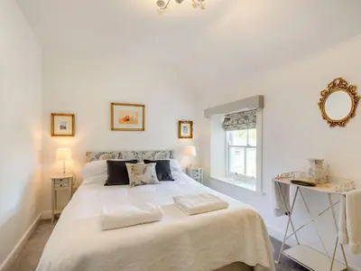 a white bedroom with a large bed and a window at Priory Walk in Newton Stewart