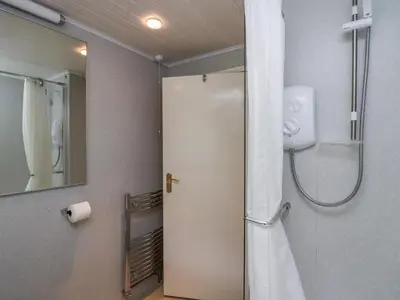 a bathroom with a shower and a toilet and a mirror at Apartment 4 in Keswick