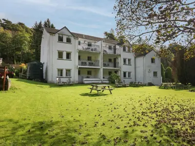 a large white building with a picnic table in a field at Apartment 1 in Keswick