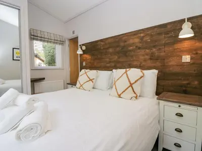 a bedroom with a white bed and a wooden headboard at The Bothy in Keswick