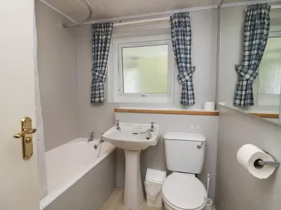 a bathroom with a toilet and a sink and a window at Apartment 2 in Keswick