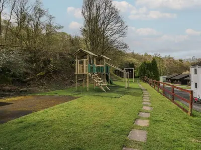 a playground in the grass next to a fence at Apartment 3 in Keswick