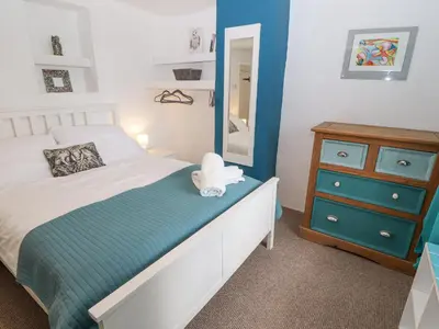 a bedroom with a bed and a dresser and a mirror at Kestrel Cottage in Keswick