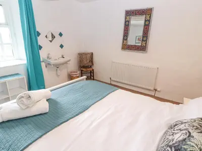 a bedroom with a bed and a sink and a mirror at Kestrel Cottage in Keswick