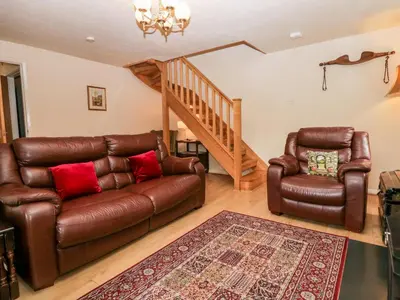 a living room with a leather couch and a chair at Thwaite How in Keswick