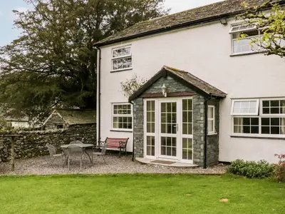 a white house with a patio and a table at Thwaite How in Keswick