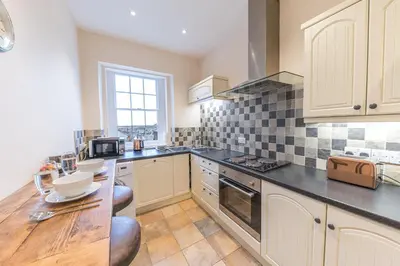 a kitchen with white cabinets and black counter tops at Town centre property convenient for the fells in Keswick