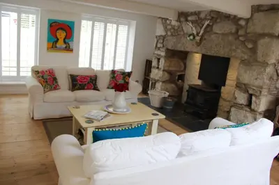 a living room with white furniture and a stone fireplace at Bridgend Cottage, Auchencairn, Castle Douglas in Auchencairn