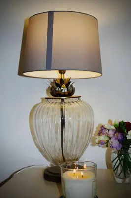 a lamp on a table with a candle and a vase of flowers at Bridgend Cottage, Auchencairn, Castle Douglas in Auchencairn