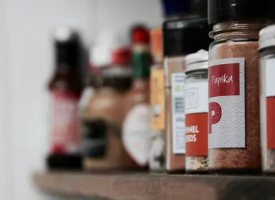 a shelf with jars of spices on it at Bridgend Cottage, Auchencairn, Castle Douglas in Auchencairn