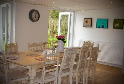 a dining room table with chairs and a clock on the wall at Bridgend Cottage, Auchencairn, Castle Douglas in Auchencairn