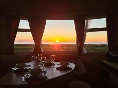 a table with two wine glasses and a view of the sunset at Tarn Bay Retreat- Sea- Fells- Beach- Views-Farm in Millom