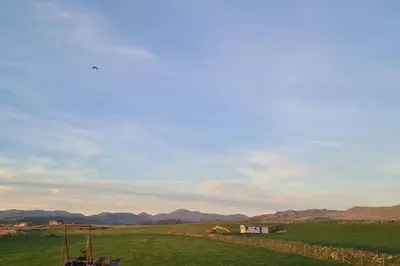 a white house in a green field with mountains in the background at Tarn Bay Retreat- Sea- Fells- Beach- Views-Farm in Millom