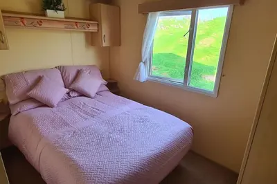 a bedroom with a purple bed with a window at Tarn Bay Retreat- Sea- Fells- Beach- Views-Farm in Millom