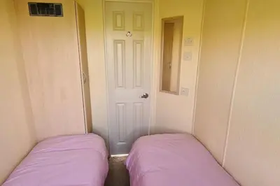 two beds in a room with purple sheets and a door at Tarn Bay Retreat- Sea- Fells- Beach- Views-Farm in Millom