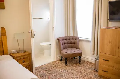 a bedroom with a chair next to a toilet at OPUL EXPRESS - Inglewood in Douglas