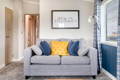 a living room with a gray couch with yellow pillows at Oak Tree Timber Holiday Lodge in Bassenthwaite