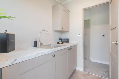 a kitchen with white cabinets and a sink at Oak Tree Timber Holiday Lodge in Bassenthwaite