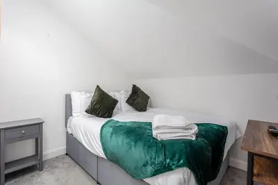 a bedroom with a bed with green sheets and pillows at Berelands House - Donnini Apartments in Prestwick