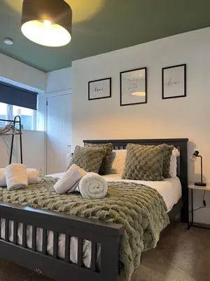 a bedroom with a large bed with pillows on it at The Boyd - Coorie Doon in Prestwick
