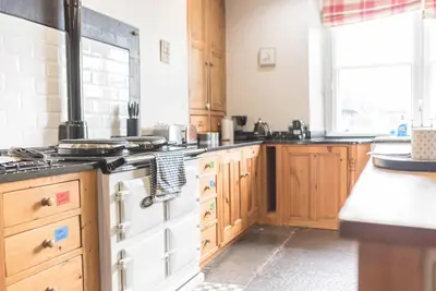 a kitchen with wooden cabinets and a white stove top oven at Historic St Bees Farmhouse Hot Tub Games Summer Gatherings in St Bees