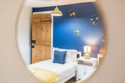 a small bedroom with a bed and a blue wall at Historic St Bees Farmhouse Hot Tub Games Summer Gatherings in St Bees