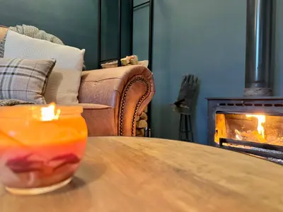 a candle on a table in front of a fireplace at Chestnut Cottage in Dalmellington