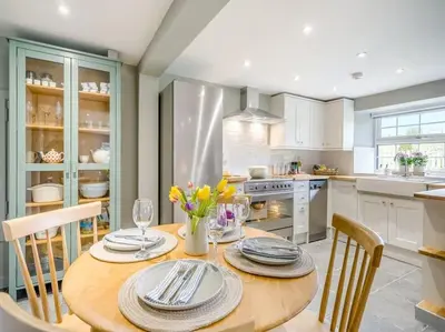 a kitchen with a wooden table with plates and flowers at Blackside Cottage - A Luxury Rural Retreat in Mauchline