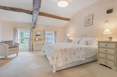 a bedroom with a large bed and a chair at farmhouse braithwaite mews in Keswick