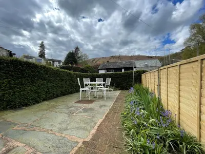 a patio with two chairs and a table in a yard at Spa Cottage in Braithwaite