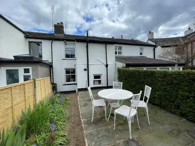 a patio with a table and chairs in front of a house at Spa Cottage in Braithwaite