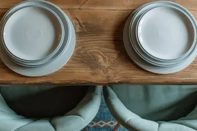 two plates sitting on a wooden table with two chairs at Grey Walls in Penrith