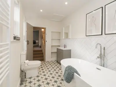 a white bathroom with a tub and a toilet at Forty Five in Keswick
