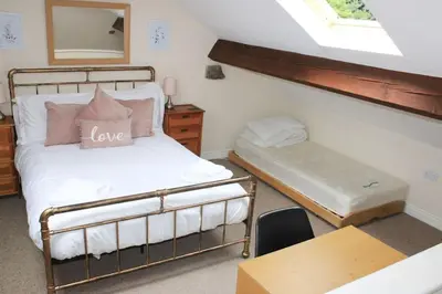 a bedroom with a bed and a desk and a window at Hillside Cottage Eskdale Green in Beckfoot
