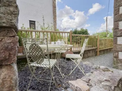 a table and two chairs sitting on a patio at Hillside Cottage Eskdale Green in Beckfoot