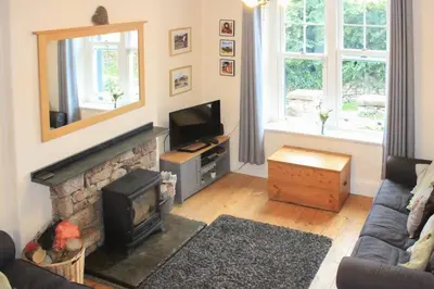 a living room with a fireplace and a television at Hillside Cottage Eskdale Green in Beckfoot