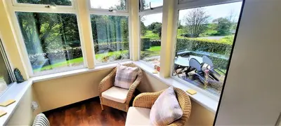 a room with two chairs and two windows at Glenterry Farmhouse in Kirkcudbright