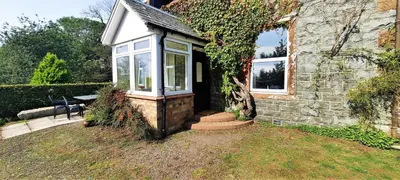 a stone house with a door and a window at Glenterry Farmhouse in Kirkcudbright