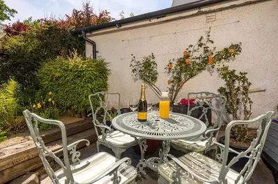 a table and chairs with two bottles of wine at Bridge Cottage Keswick in Keswick