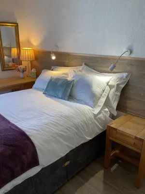 a large bed with white sheets and blue pillows at The Hutchinson Apartments in Douglas