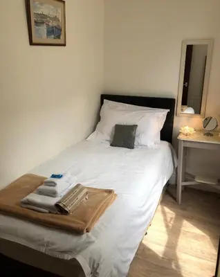 a white bed with a tray of towels on it at The Hutchinson Apartments in Douglas