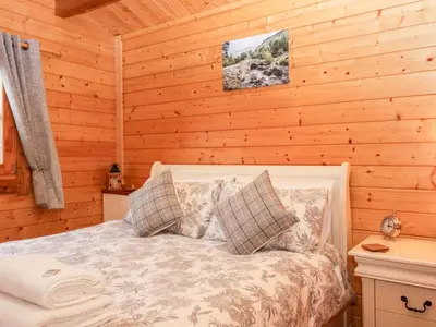 a bedroom with a bed in a log cabin at Ballinorig Lodge in Cleator Moor