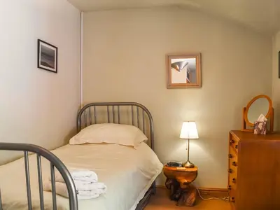 a small bedroom with a bed and a dresser at Church House Cottage in Ulpha